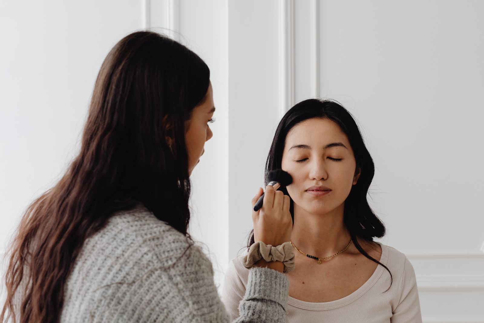 Makeup artist applying blush in a bright private studio